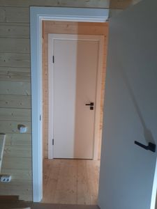 В деревянной двери аккуратно проделано отверстие, установлена фурнитура, закреплены ручки, проверена функциональность механизма, обеспечена плавная работа.