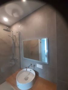 Установлено прямоугольное зеркало над раковиной в ванной комнате. Закреплено на стене с учётом уровня и симметрии, обеспечена надёжность креплений и эстетичность расположения.