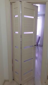 Установлена складная дверь светлого оттенка с горизонтальными вставками, обеспечивающая удобство и экономию пространства в интерьере.