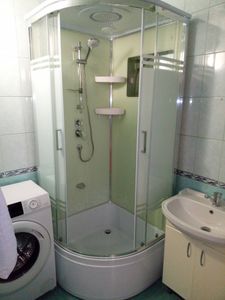 Установлена душевая конструкция с низким основанием, подключены водопровод и слив, закреплены стенки и двери, проверена герметичность и функциональность, добавлены полки для удобства.