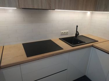 Установлена новая поверхность из ДСП, выполнены вырезы для варочной панели и мойки, произведена герметизация стыков, закреплены детали, подключены коммуникации для воды и электричества.