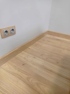 Установлен скрытый плинтус, аккуратно прилегающий к стене и полу, создающий плавный переход. Завершение работ подчёркивает чистоту линий и гармонию интерьера.