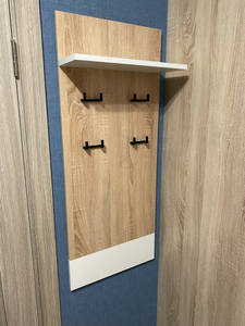 Закреплена деревянная панель на стене, установлены металлические крючки для одежды, добавлена верхняя полка для хранения. Компактная конструкция завершена, готова к использованию.