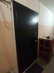 Изображение демонстрирует завершённый монтаж металлической двери. Установлена новая конструкция, произведена регулировка петель, закреплён замок, проверена функциональность.