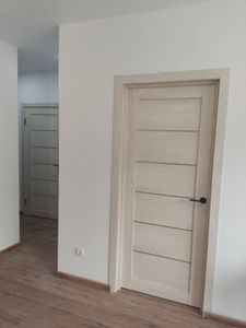 Установлена светлая дверь с горизонтальными вставками, врезана ручка, закреплены петли, отрегулировано полотно, выполнена отделка проема, добавлены наличники, завершена финишная отделка.