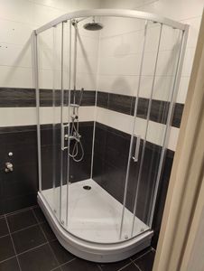 Установлен душевой уголок: закреплены стеклянные панели, поддон, смеситель и лейка. Подключены водопроводные трубы, проверена герметичность соединений. Завершено оформление пространства.