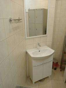 Зеркало аккуратно закреплено на стене ванной комнаты над раковиной. Установлено ровно, надежно, без видимых крепежных элементов. Подходит по размеру, гармонирует с интерьером.