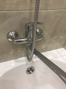 Изображение демонстрирует завершенный монтаж сантехники: установлены смеситель, душевая лейка и слив в ванной. Все элементы надежно закреплены и подключены к водопроводу, обеспечивая функциональность.