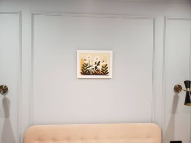На стене закреплено изображение в рамке с цветочным мотивом. Композиция расположена симметрично, гармонирует с интерьером. Работа выполнена аккуратно, без видимых креплений.