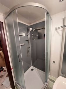 Установлена конструкция с низким основанием: закреплены стенки, двери, подключены коммуникации, проверена герметичность, смонтированы полки, установлены душевые аксессуары.