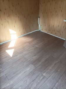 В комнате уложено новое напольное покрытие. Панели аккуратно состыкованы, создавая ровную поверхность. Углы и стыки обработаны, обеспечивая эстетичный вид и долговечность.