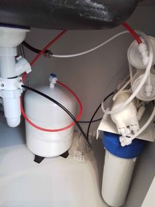 Установлено устройство для очистки воды под раковиной. Подключены трубки, закреплены крепления, проверена герметичность соединений. Система готова к использованию.