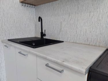 Установлена новая столешница из ДСП, вырезано отверстие под мойку, закреплены края, подключен смеситель, проверена герметичность соединений, завершена отделка поверхности.