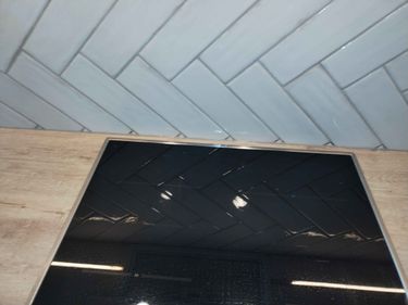 Уложена плитка на стену в виде "елочки", установлена варочная панель на кухонную поверхность. Завершено оформление рабочей зоны.