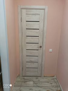 Установлена деревянная створка, закреплены петли, врезана ручка, отрегулированы зазоры, выполнена отделка наличниками, обеспечена плавность открывания, завершено оформление проема.