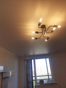 На потолке закреплено осветительное устройство с несколькими лампами. Все элементы установлены и подключены, обеспечивая равномерное освещение в комнате.