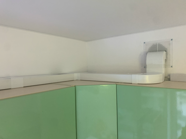 Установлена система воздуховодов: трубы аккуратно проложены вдоль стены, соединены с вытяжным отверстием. Все элементы надежно закреплены, обеспечивая эффективную вентиляцию.