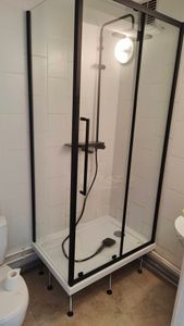 Установлена стеклянная конструкция с черными рамами, закреплена на поддоне с регулируемыми ножками. Подключены водопроводные элементы, обеспечена герметичность соединений.