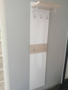 Закреплена настенная панель с крючками и полкой. Установлена конструкция для хранения одежды, обеспечивающая удобство и функциональность в интерьере.