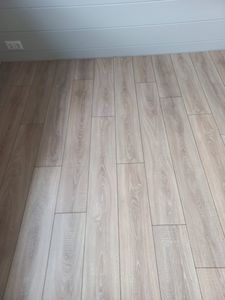 Уложено новое покрытие, ровные панели светлого оттенка, без зазоров. Пол полностью обновлён, создаёт уютную атмосферу в помещении.