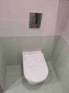 Закреплена система для подвесного унитаза, выполнены все необходимые подключения, установлена кнопка смыва, облицовка завершена, обеспечена надежная фиксация и герметичность конструкции.