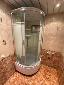 Установлена душевая конструкция с низким основанием, закреплены стеклянные панели, подключены водопровод и слив, герметизированы соединения, проверена функциональность.