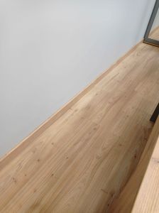 Установлен скрытый плинтус, аккуратно интегрированный в стену. Завершено выравнивание и фиксация, обеспечивающие плавный переход между полом и стеной, создавая современный и чистый вид.