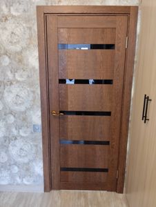 Установлена новая дверь: закреплена коробка, навешено полотно, врезаны петли, прикреплена ручка, отрегулированы зазоры, обеспечена плавная работа, завершена отделка наличниками.