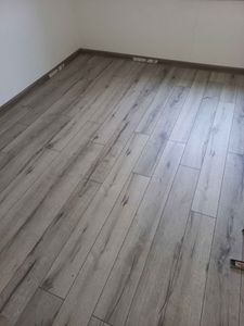 Завершена укладка напольного покрытия: панели аккуратно размещены на ровной поверхности, стыки плотно соединены, установлены плинтусы, обеспечивая завершенный вид и долговечность.