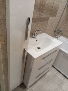 Изображение ванной комнаты с белой раковиной, шкафом и ванной. Установлены элементы для работы кондиционера в холодное время года: обогреватель картера, регулятор оборотов вентилятора и обогрев дренажа.