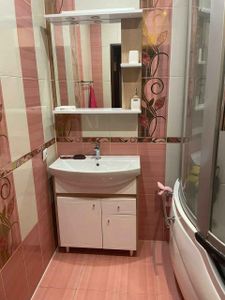 Зеркало надежно закреплено на стене ванной комнаты над раковиной. Установлены полки для удобства хранения. Работа выполнена аккуратно, без видимых дефектов, с учетом дизайна интерьера.