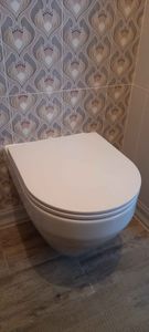 Закреплена конструкция для подвесного унитаза, подключены коммуникации, установлена чаша, выполнена облицовка плиткой. Все элементы надежно зафиксированы, система готова к эксплуатации.