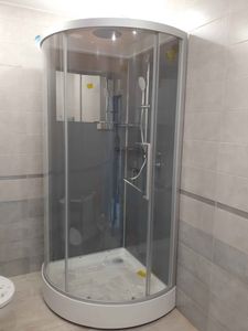 Установлена стеклянная кабина с герметичными дверцами, подключены смеситель и лейка, закреплён поддон, проверена герметичность соединений, завершены отделочные работы, обеспечена функциональность.