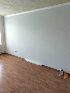 Стену освободили от старого покрытия, поверхность очищена, подготовлена для дальнейших работ. Полы и плинтусы оставлены в порядке, мусор убран, помещение готово к обновлению интерьера.