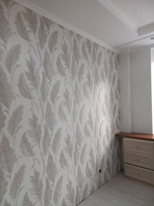 Стены покрыты стеклохолстом с узором, создающим текстурный эффект. Поверхность ровная, без видимых швов, с аккуратными стыками. Декор завершен, комната приобрела стильный вид.