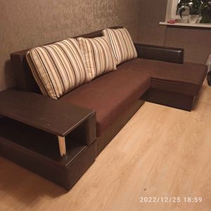 Собран угловой диван с подлокотником и полкой. Установлены подушки, закреплены все элементы, проверена устойчивость конструкции. Завершена работа по монтажу и проверке качества.