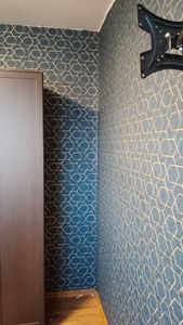 На стенах наклеены фотообои с геометрическим узором, создающим стильный и современный вид. Углы и стыки аккуратно обработаны, обеспечивая ровное прилегание и безупречный внешний вид.