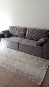 Собран новый диван: установлены подлокотники, закреплены спинки, прикреплены ножки, добавлены подушки. Все элементы соединены, конструкция устойчива, готова к использованию.