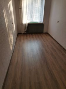 Покрытие из ламината уложено на ровное основание, обеспечивая гладкую и эстетичную поверхность. Пол выглядит аккуратно, без зазоров, создавая уютную атмосферу в помещении.