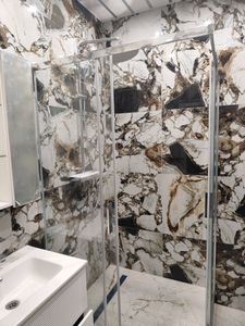 Установлены стеклянные перегородки, закреплены металлические профили, смонтирован душевой поддон, подключены водопроводные трубы, проверена герметичность соединений, выполнена отделка плиткой.