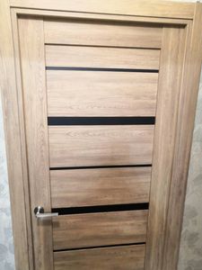 Установлена новая деревянная створка, закреплены петли, врезан замок, смонтирована ручка, отрегулированы зазоры, проверена плавность хода, выполнена отделка проема, завершены все монтажные работы.