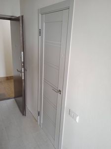 Изображена установленная складная дверь, закрепленная в проеме. Завершены монтажные работы, включая фиксацию направляющих, крепежа и ручек. Конструкция гармонично вписывается в интерьер.