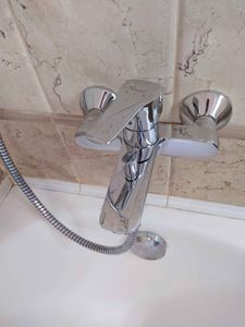 Изображен завершенный процесс снятия смесителя с раковины. Удалены крепления, отключены водопроводные шланги, устранены остатки герметика. Место подготовлено для установки нового оборудования.