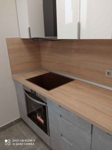 Изображена современная кухня с новой варочной панелью и вытяжкой. Белые шкафы и деревянная столешница создают стильный интерьер.