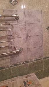 Уложена керамика на стены, швы затерты, установлены декоративные элементы, смонтирован полотенцесушитель. Поверхность ровная, аккуратная, без дефектов. Завершено оформление.