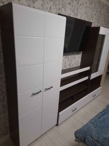 Собрана мебельная конструкция: установлены шкафы, полки, ящики. Все элементы соединены, дверцы навешаны, ручки прикреплены. Композиция завершена, установлена на место.