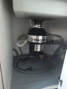 Установлен и подключен измельчитель под раковиной, подключены трубы и электропитание, проверена герметичность соединений, устройство готово к использованию.