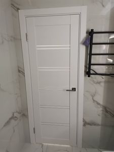 Изображена установленная дверь-гармошка в светлом интерьере. Завершены монтажные работы, включая крепление направляющих и фиксацию полотна. Дверь аккуратно вписана в проем.