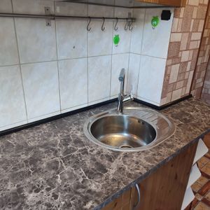 Установлена новая столешница с мраморным узором, врезана раковина, подключен смеситель. Обновлены настенные крючки для удобства хранения кухонных принадлежностей.