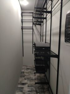 Установлен металлический турник в узком помещении, закреплён на стене. Стойки и перекладины надежно зафиксированы, обеспечивая устойчивость и безопасность использования.